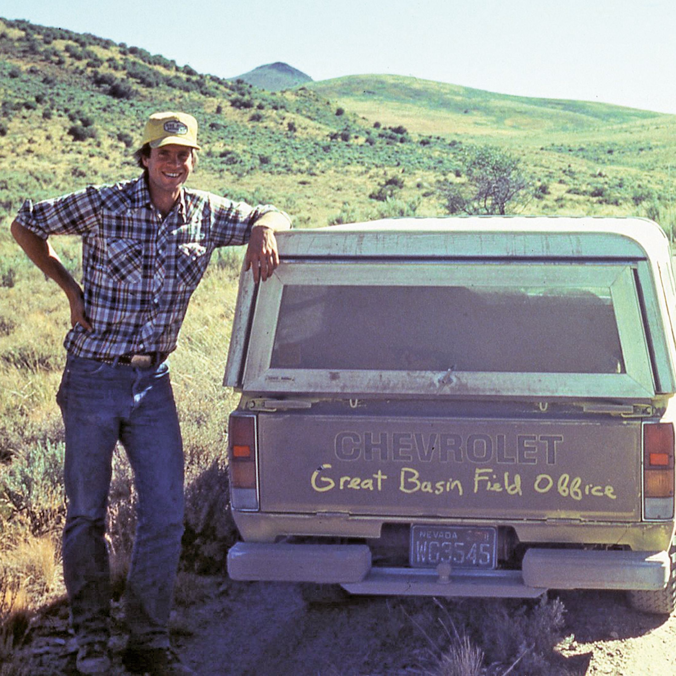 Dave Livermore standing next to truck on a dirt road in desert landscape with rolling hills.