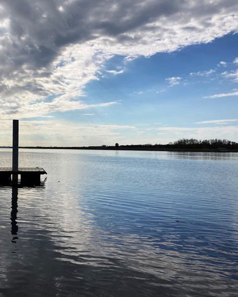 Calm waters surround a dock under a cloudy sky.