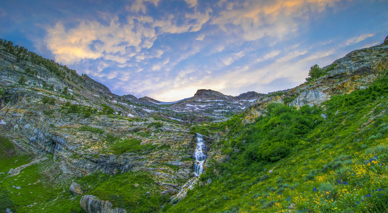 Waterfall flowing down mountains with a blue sky.