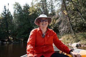 Jill Heinerth with glasses and a floppy hat sitting in a boat.