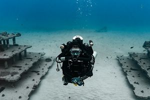 A woman in dive gear swims through an artificial reef.
