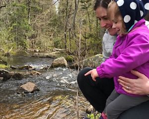 Eileen Bader Hall and her daughter watch as alewives migrate in a newly restored stream in Maine.