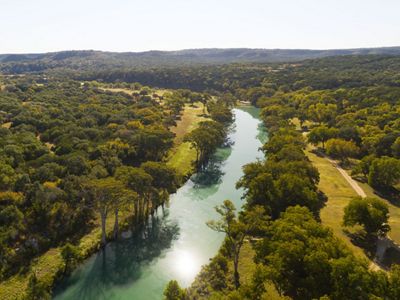 A turquoise blue river lined with tall, green trees.
