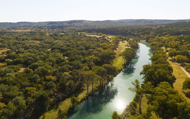 A blue river lined with dense green trees.