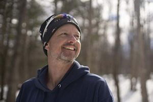 Man wearing a beanie hat in the winter smiling looking at the distance.