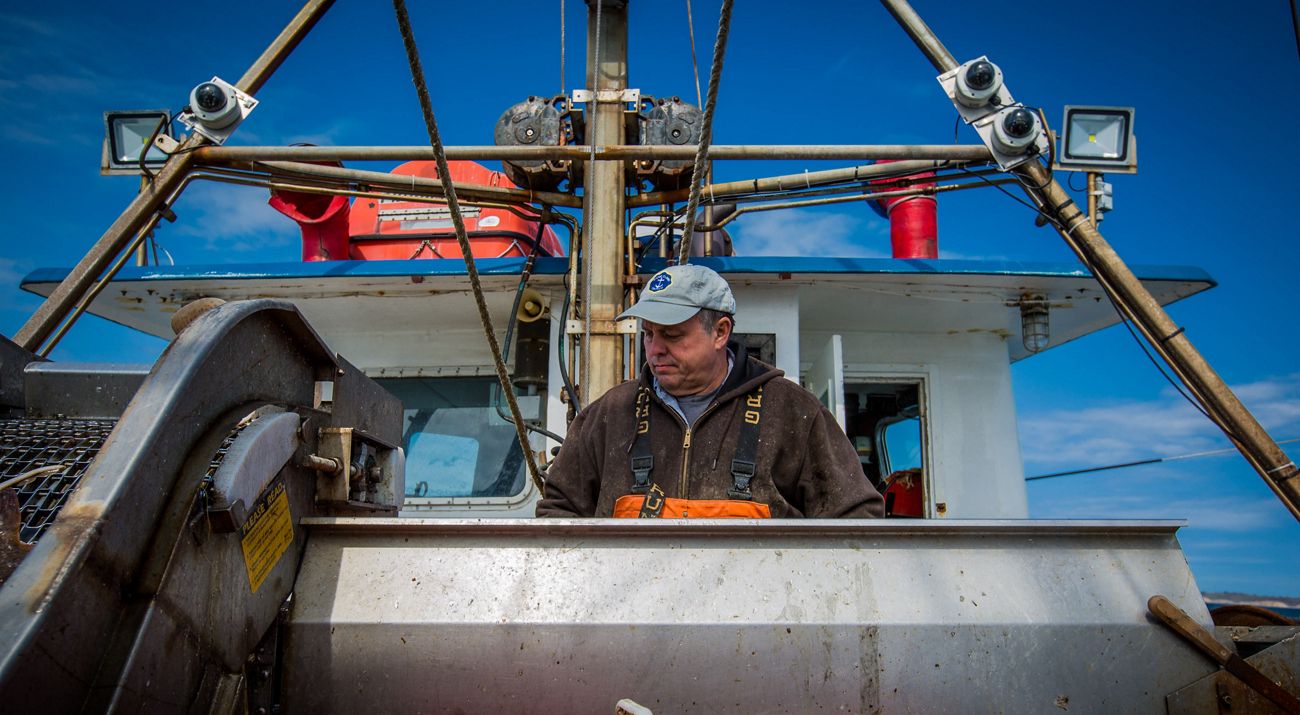 A fisherman on a New England commercial fishing vessel checks his nets as a fixed video camera records the work.