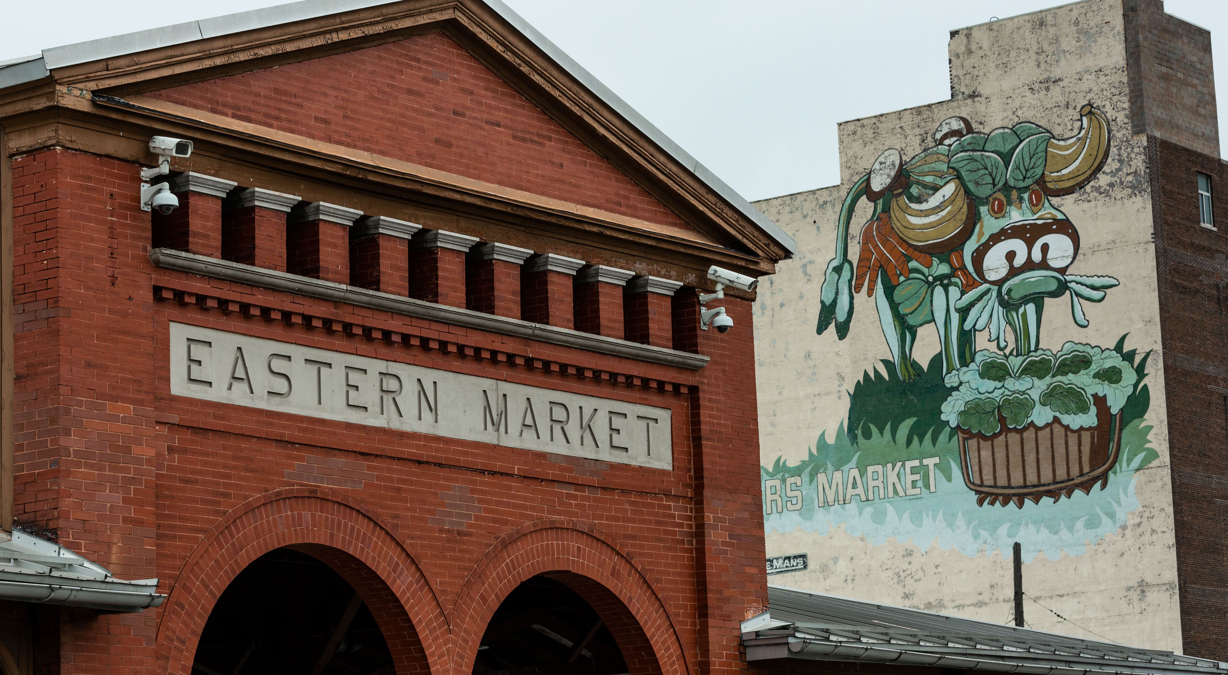 Red brick building for Eastern Market next to building with mural.