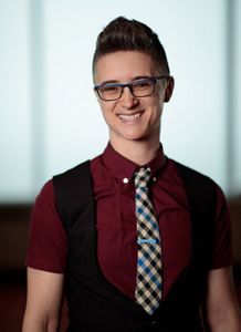 A person wearing glasses, maroon shirt and tie. 