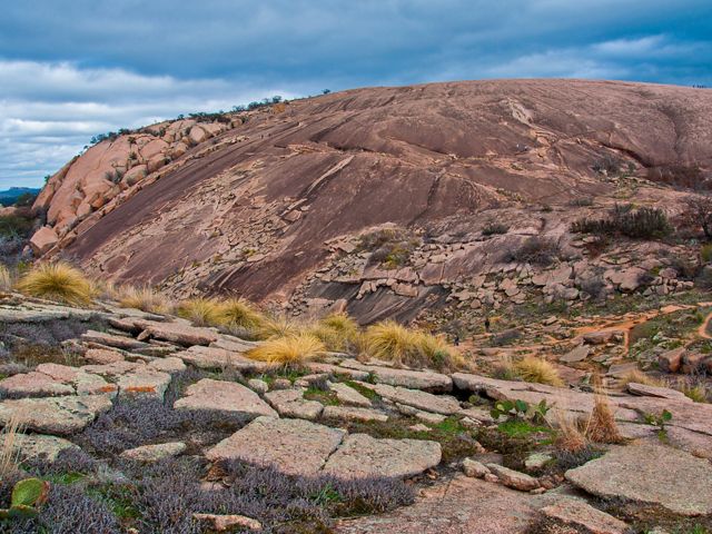 Un monte de granito rosado de cerca en primer plano, con el punto mas alto detrás.
