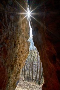 Sunlight shines through a crevice between two rock walls.