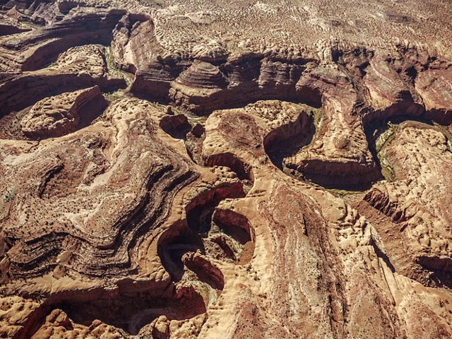 Aerial view of a meandering river that has cut a deep, terraced canyon in the tan rocks.