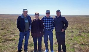 Four people smile in front Tallgrass Prairie Preserve.
