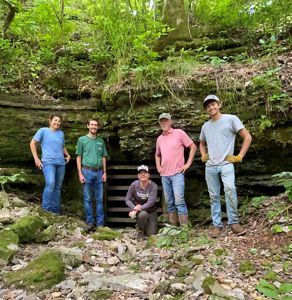 The Eucha Gate Team standing in front of a gated opening that protects an entrance into the subterranean ecosystems below.  