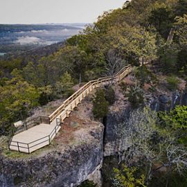 A tall rocky outcropping with wooden boardwalk and platform overlook juts out of the forest at Edge of Appalachia Preserve.