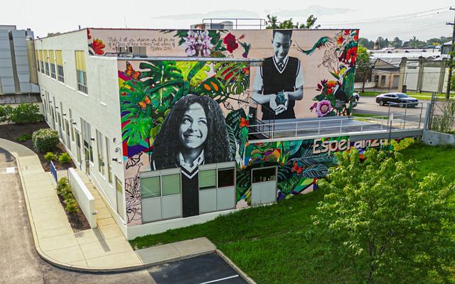 A buidling with a colorful mural sits in the cetner of a city block.