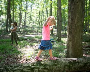 Young girl balances on white ash trunk