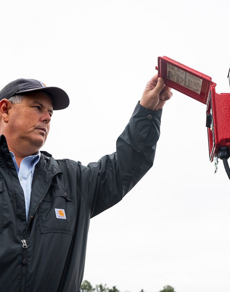 Man checks on a red irrigation pump timer in this field