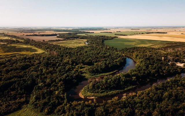 A river surrounded by trees and farmlands.