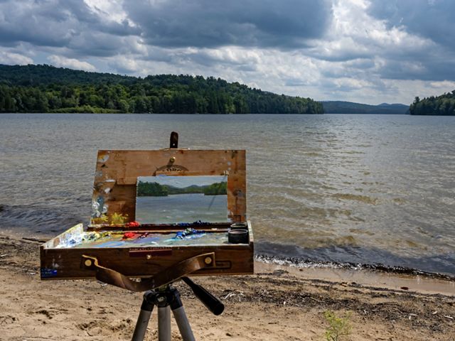 A canvas with a painting of the river in front of the river.