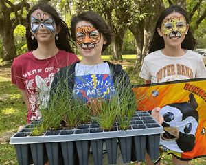 Three children hold longleaf pine seedlings as part of the Sewee Fire Festival in South Carolina.