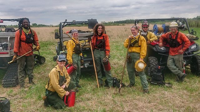 A group of fire practitioners posing proudly at a burn site.