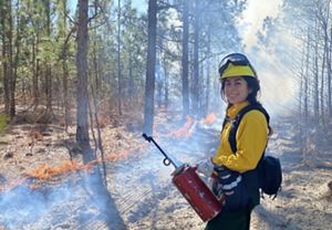 Sophia holding a drip torch during a controlled burn.