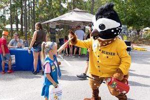 Little girl giving a person on a bobwhite quail costume a high five.