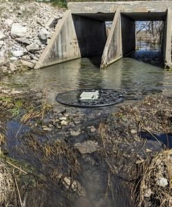 A round floating antenna placed just past a concrete culvert in a stream.