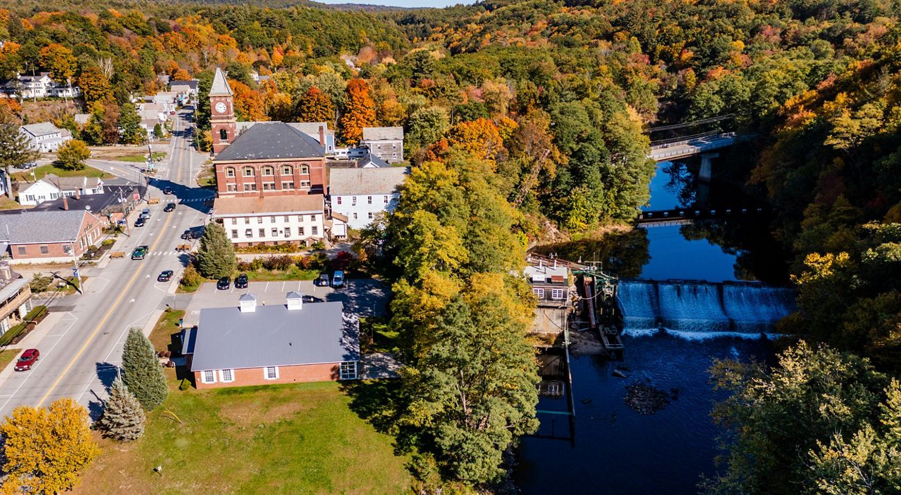 An overhead view of a dam in river meandering through a mill town.
