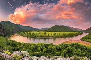 The confluence of the Eg (Egiin Gol) and Tarvagatai rivers in central Mongolia under a sky filled with orange and pink clouds at sunset.