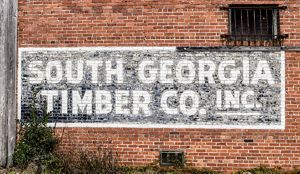A black and white sign is painted on a red brick building.