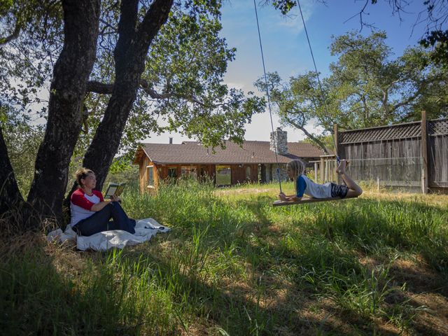 Scientist Heather Tallis sits under a tree at her house in California facing her son on a swing. 