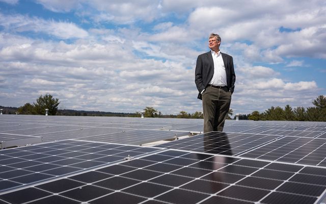 David Worthen, owner of Worthen Industries in Nashua, N.H., stands between more than 2700 solar panels installed on the roof of his adhesive manufacturing plant. Last summer, David invited New Hampshire’s governor to tour Worthen Industries and hosted a roundtable discussion about investing more money in renewables in the state.