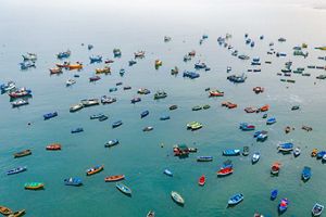 Colorful fishing boats sitting on still blue water.