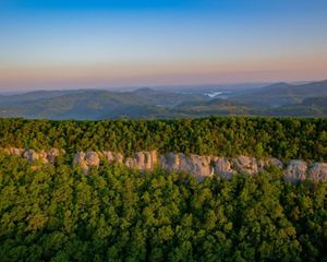 Aerial view of a forest-covered rock ridge with mountains in the distance.
