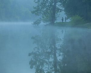 anglers fish on a misty lake