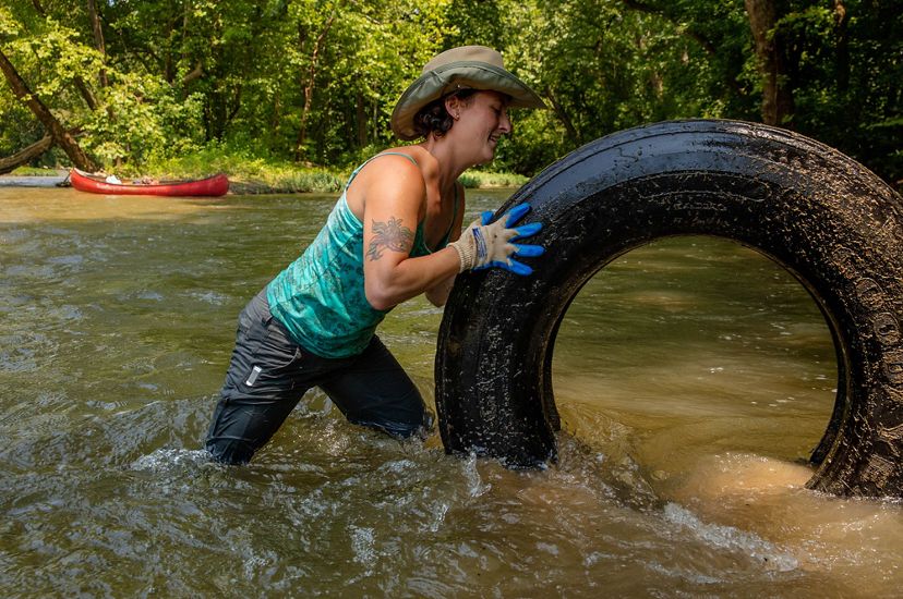A woman removes a tire from a river