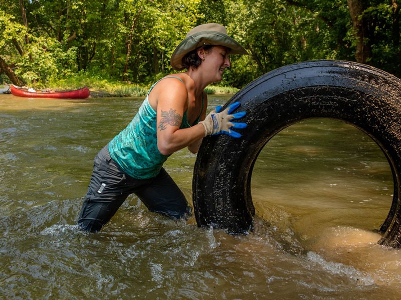 Una mujer saca una llanta de un río
