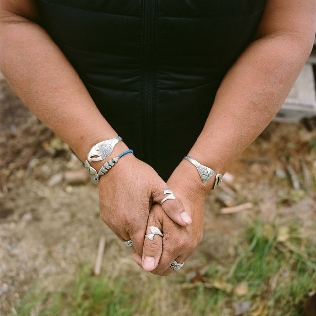 close up of hands and wrists with multiple silver rings and bracelets in the shape of fish