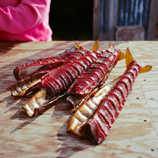 several pieces of sliced red fish meat lay piled on a wooden board