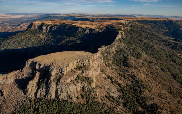 An aerial shot of Fishers Peak in Colorado showing a rugged, rocky backbone of mountains and canyons stretching to the horizon. 