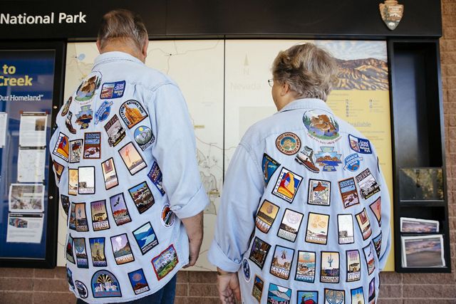A couple wears shirts covered in patches from national parks.