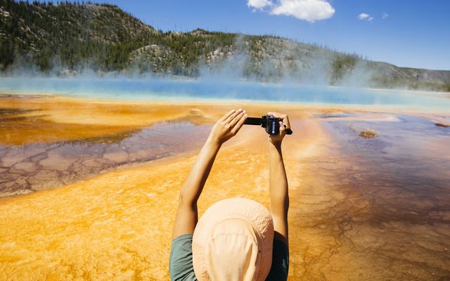 A tourist takes a photo of the Grand Prismatic Spring in Yellowstone National Park.