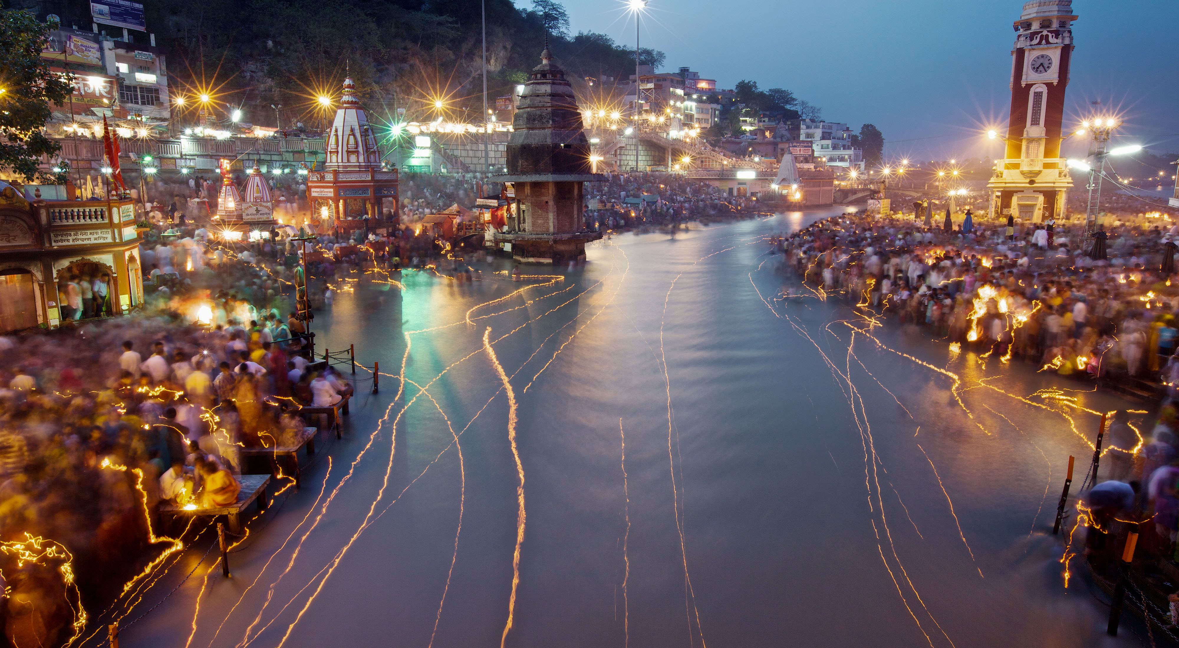 The Ganges River in India at night, reflecting the lights of buildings and passing boats
