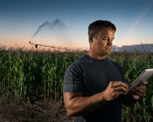 A farmer in a field uses a tablet to control irrigation
