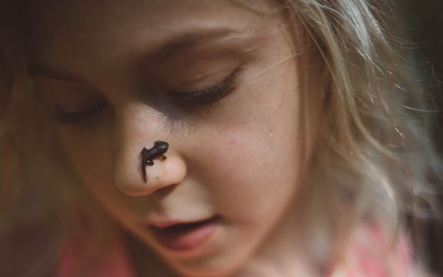 Closeup of a girl with a tadpole on her nose.