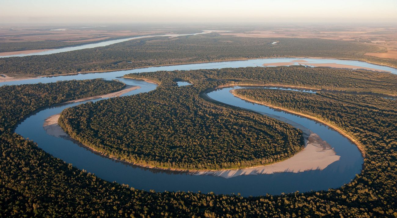 River bend with trees at sunset.