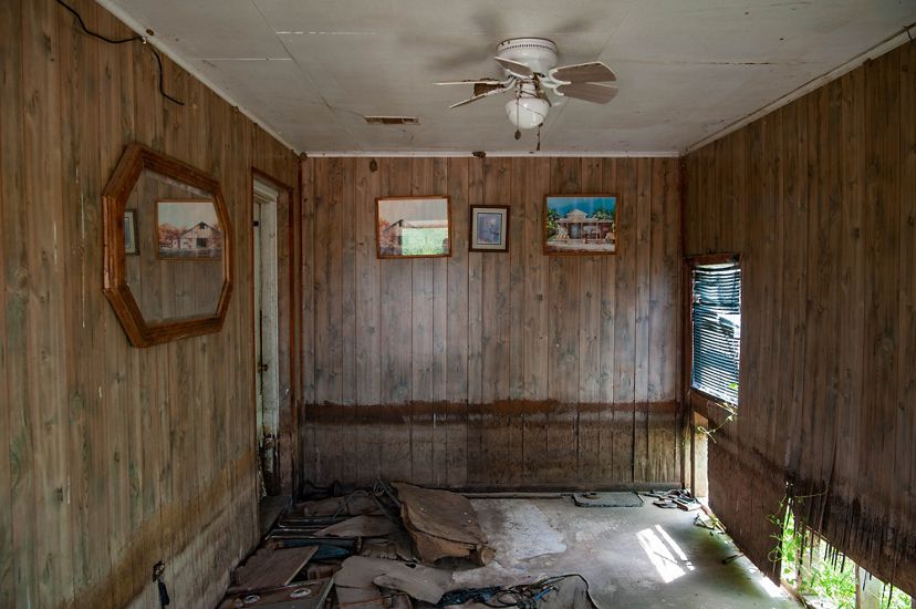 A wood-paneled room shows damage below a brown waterline stain.