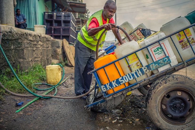 A man fills plastic containers on a cart with water