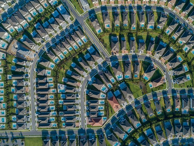 Aerial view looking directly down on an Orlando area neighborhood with densely packed houses, each with a backyard swimming pool, along curving suburban streets..